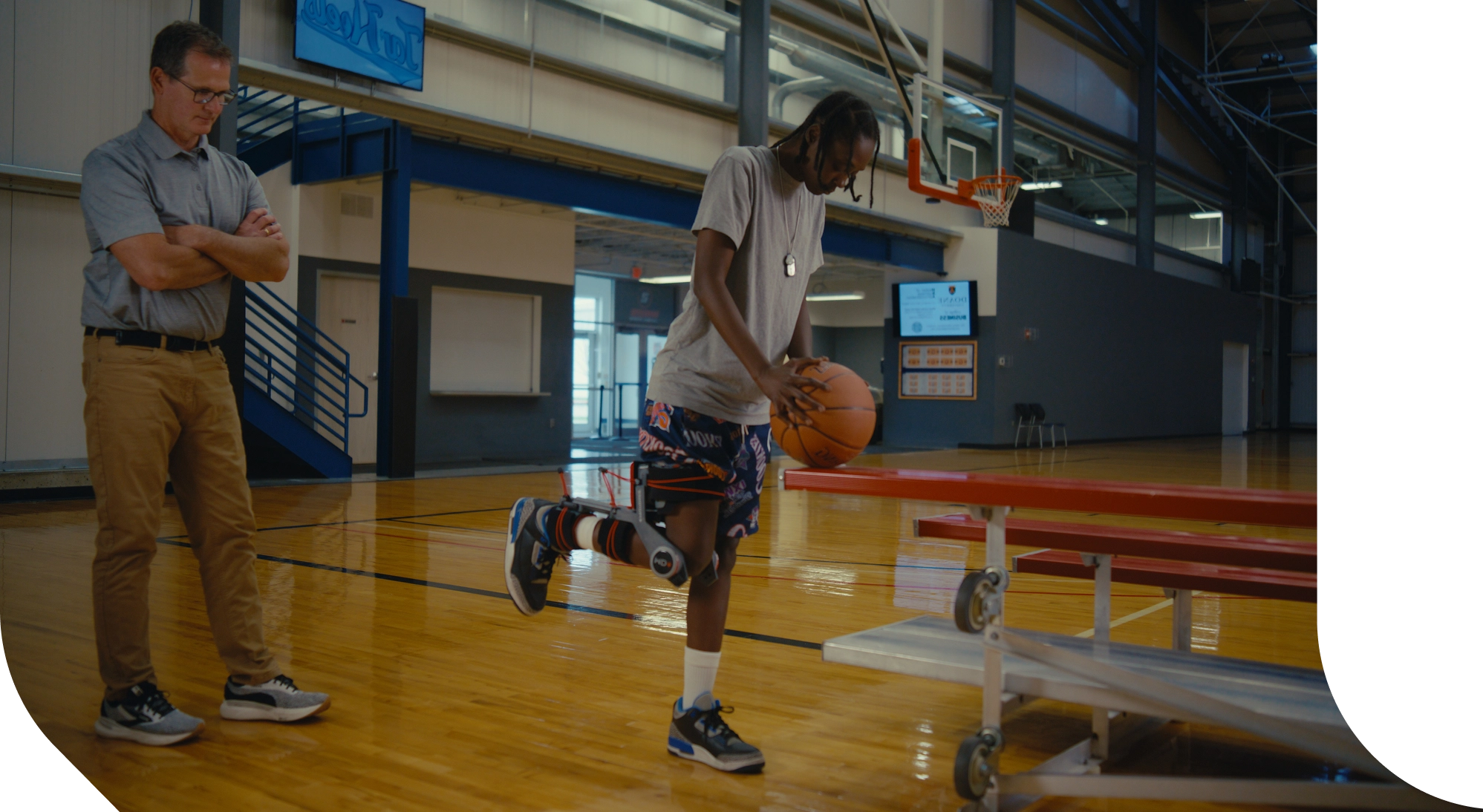 Basketball player using a MD+ device with a coach observing in a gymnasium.
