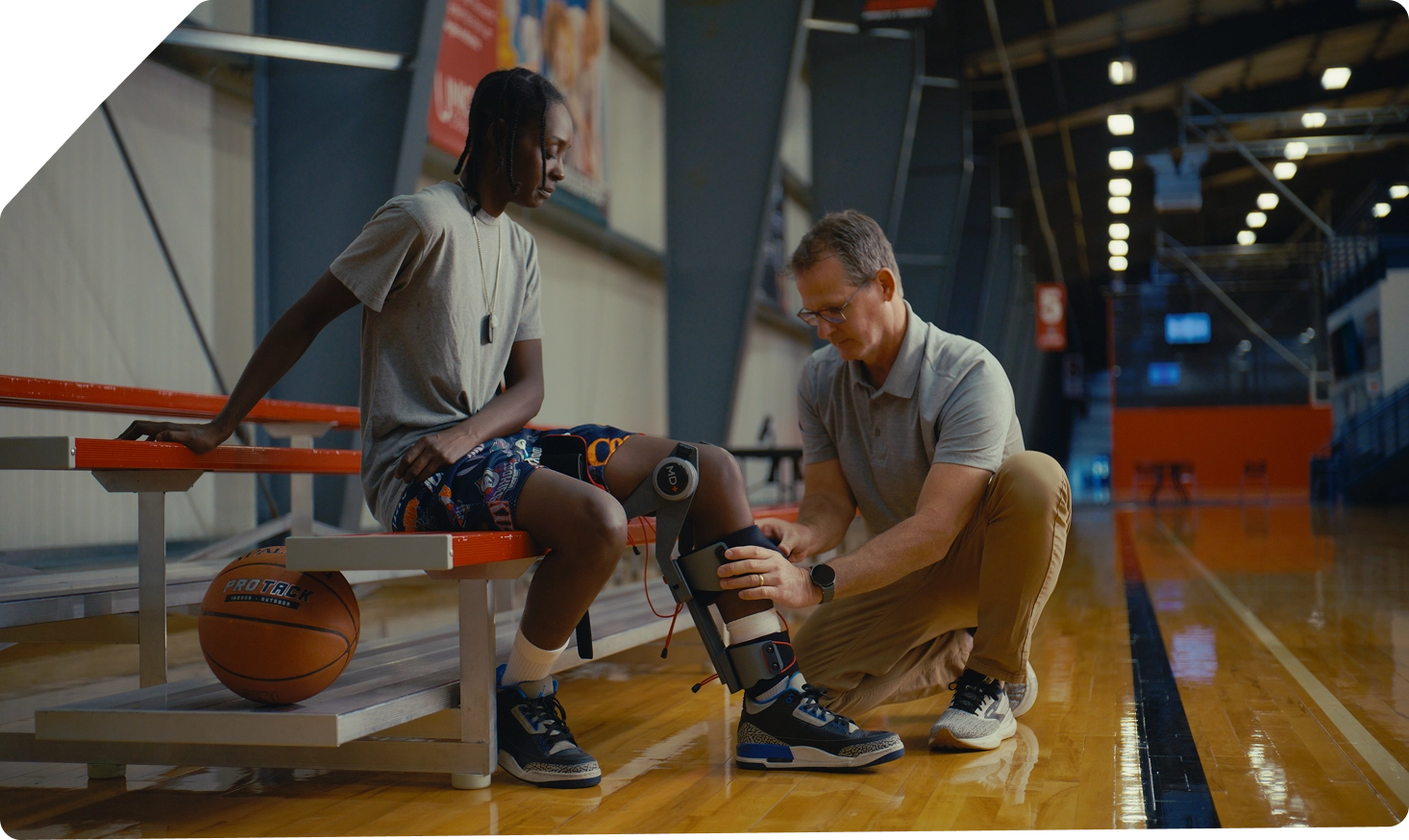 Person with a MD+ device receiving assistance from another person on a basketball court.